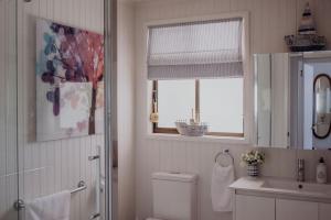 a bathroom with a toilet and a sink and a window at Sea Breeze Freycinet - Hot Tub in Coles Bay +26 photos