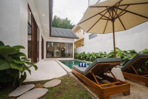 a patio with a chair and an umbrella and a swimming pool at Villa Shekinah Oasis in Ubud