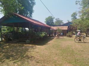 a person riding a bike in front of a building at Bounhome Guesthouse in Don Det