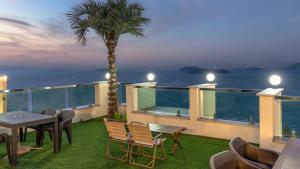 a balcony with a table and chairs and a palm tree at Yeosu Hemiswi SPA Pension in Yeosu