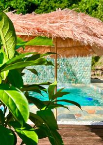 a large straw umbrella next to a swimming pool at Les Chalets de Afaahiti - Fare Keanu in Tiitau
