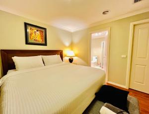Un dormitorio con una gran cama blanca y un baño. en An Ensuite Comfort in Sydenham, en Sydenham