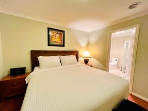 Un dormitorio con una gran cama blanca y un baño. en An Ensuite Comfort in Sydenham, en Sydenham