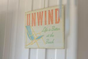 a sign hanging on a wall with a beach chair at The Golden Beach Residence in Golden Beach