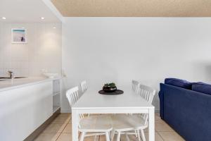 una mesa blanca y sillas en una cocina con sofá azul en Bellardoo12- Mooloolaba Beach, en Mooloolaba 8 fotos más