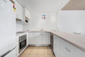 a white kitchen with white cabinets and a sink at Bellardoo12- Mooloolaba Beach in Mooloolaba +9 photos