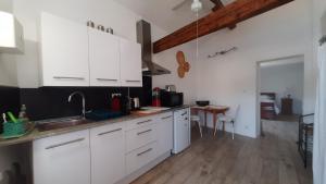 a kitchen with white cabinets and a wooden floor at Belle vue in Agde +15 photos