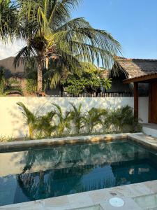 a swimming pool in front of a house with a palm tree at Pink Door Villa Gili Air, private pool & kitchen in Gili Air