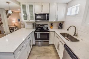 een keuken met witte kasten, een fornuis en een wastafel bij Vibrant & Cozy Two Bedroom Lower Unit King Beds in Denver +9 foto's