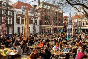 a crowd of people sitting at tables in front of buildings at Stayci Serviced Apartments Westeinde in The Hague