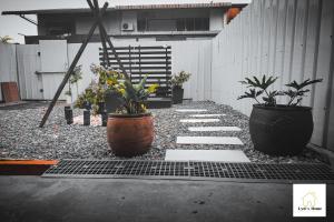 a garden with three potted plants on a sidewalk at Lyd's Home Urban Staycation in Sibu