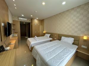 a hotel room with two beds and a flat screen tv at Apartment Nagoya Thamrin favehotel in Nagoya