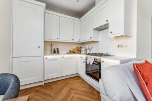 Una cocina blanca con gabinetes blancos y una estufa. en Beachside Maisonette Southbourne, en Bournemouth