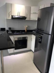 a kitchen with a black refrigerator and white cabinets at Apartamento Hacienda Peñalisa in Ricaurte