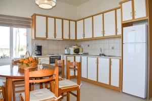 Una cocina con gabinetes blancos y una mesa y sillas. en Lily of Crete 1 - Sea & Beach front Apartment, en Kalamaki 23 fotos más
