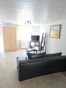 a living room with a black couch and a table at Appartement proche Colmar in Soultzbach-les-Bains