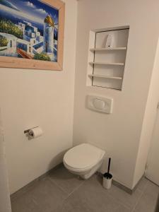 a bathroom with a toilet and a painting on the wall at Appartement proche Colmar in Soultzbach-les-Bains +3 photos