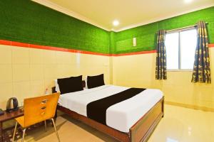 1 dormitorio con cama, escritorio y paredes verdes en Hotel O MAK RESIDENCE, en Shamshabad