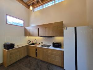 una cucina con mobili in legno e un frigorifero bianco di Baan Prod Pool Villa Chiang Mai a Chiang Mai