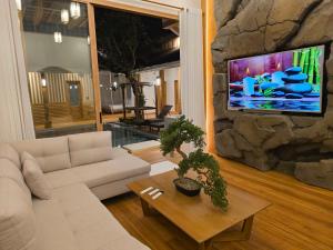 un soggiorno con divano e TV su un muro di pietra di Baan Prod Pool Villa Chiang Mai a Chiang Mai