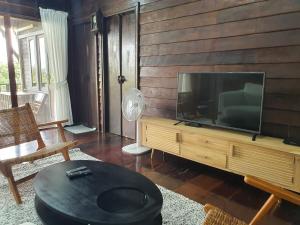 a living room with a flat screen tv on a wooden wall at Baan Marrada Garden in Ban Pak Khlong Khwang