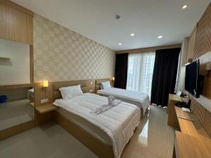 a hotel room with two beds and a flat screen tv at Apartment Nagoya Thamrin favehotel in Nagoya