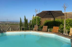 ein Schwimmbecken mit zwei Stühlen und einem Sonnenschirm in der Unterkunft Cal Castlà in La Granada