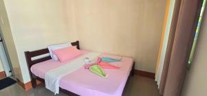 a small room with a pink bed with towels on it at OYO 1121 JUNLYN APARTELLE in Panglao Island