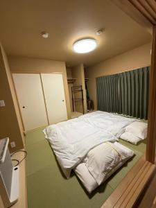 a bedroom with a large bed with white sheets at GREEN ViLLA南大阪 in Mikkaichi