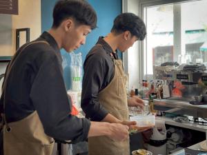 two men standing in a kitchen preparing food at Belivin'98 Sense of Pier Sathorn Residence in Bangkok