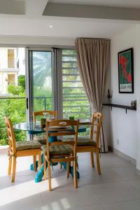 Un comedor con una mesa de cristal y sillas. en Seabreeze Mont Choisy Apartment, en Trou aux Biches