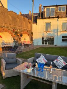 a patio with a couch and a table in a yard at High Tide Beach House on waters edge in Bangor