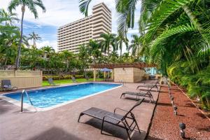 une piscine avec des chaises et un bâtiment dans l'établissement Aloha Seaside Vacations 4 Star Wyndham Resort 1803 Waikiki, à Honolulu