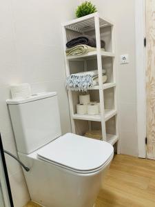 a bathroom with a toilet and a shelf with towels at Chipiona Center in Chipiona