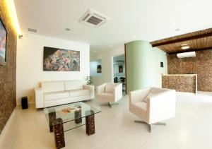 uma sala de estar com mobiliário branco e uma pintura na parede em Pousada Eco Maceio em Maceió