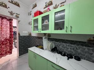 a kitchen with green cabinets and a bathroom at Anemon Stays in Marakkānam