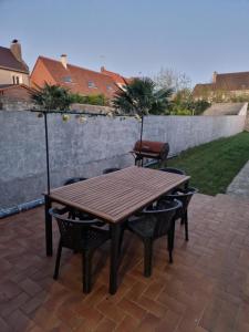 a wooden table and chairs on a brick patio at Maison familiale 6 pers ,1 bébé in Étaples