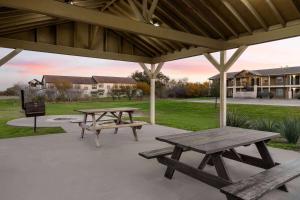 two picnic tables and benches under a pavilion at Eagle's Den Suites Kenedy a Travelodge by Wyndham in Kenedy