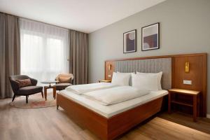 a bedroom with a large bed and a chair at Ramada by Wyndham Duesseldorf Ratingen in Ratingen