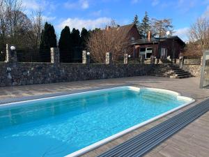 a swimming pool in a yard next to a stone wall at Ferienhaus MILA - Pool, Sauna, Whirlwanne, 5000qm Privatgelände mit Bolzplatz in Striesdorf
