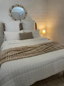 1 dormitorio con 1 cama blanca grande y espejo en Baybreeze Flatlet, en Ciudad del Cabo