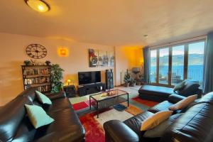 a living room with a leather couch and a television at Pianello Bellavista in Pianello Del Lario