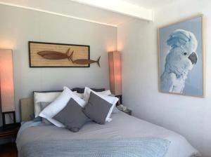 a bedroom with a bed with a painting on the wall at Cosy retro styled bungalow in Narrawallee