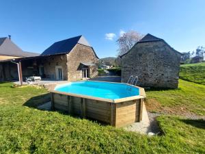 a swimming pool in front of a stone house at Maison Labeye - gîte 4 étoiles calme avec jacuzzi et piscine in Cardesse