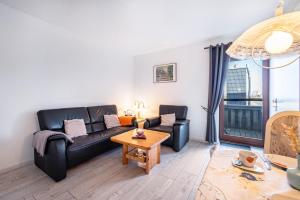 a living room with a black couch and a table at Ferienwohnungen Hof Am Deich in Hillgroven