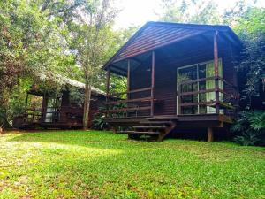 a wooden cabin with a porch and a grass yard at Fountain Baths Guest Cottages in Barberton