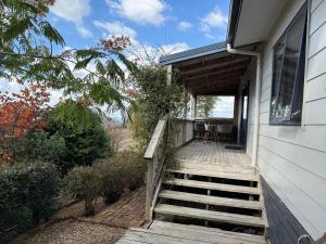 a house with a wooden staircase leading to a porch at Cosy Country Private Cottage with views in Harapepe