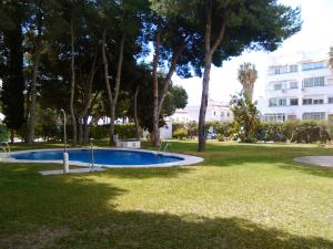 een zwembad in een park met bomen en een gebouw bij APARTAMENTO PINAR de MONTEMAR in Torremolinos