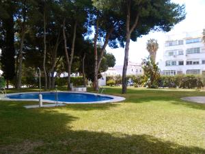 a swimming pool in a park with trees and a building at APARTAMENTO PINAR de MONTEMAR in Torremolinos