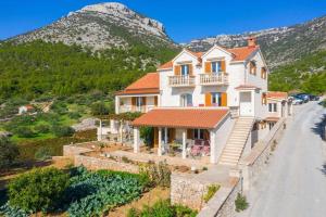 a large white house with a mountain in the background at Apartman Dinko in Bol